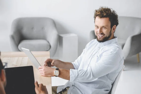 Retrato de homem de negócios sorrindo usando tablet enquanto conversa com colega no escritório — Fotografia de Stock