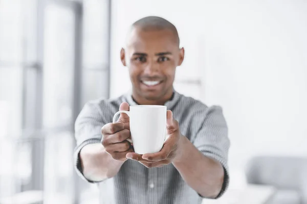 Foco seletivo do empresário afro-americano segurando xícara de café nas mãos — Fotografia de Stock
