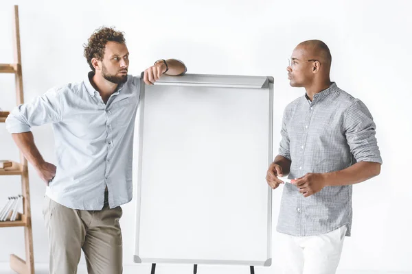 Uomini d'affari multietnici in piedi vicino a bordo bianco durante la presentazione aziendale — Foto stock