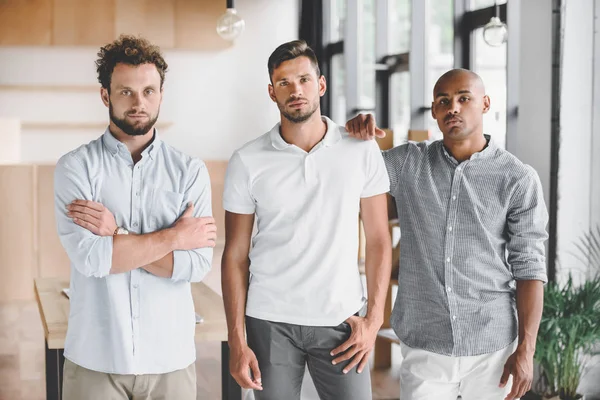 Multiethnische junge Geschäftsleute blicken im Büro in die Kamera — Stockfoto