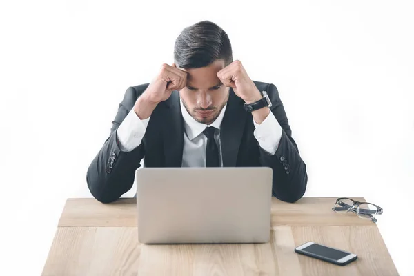 Retrato de hombre de negocios cansado sentado en el lugar de trabajo con computadora portátil y teléfono inteligente aislado en blanco - foto de stock