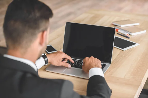 Back view of businessman working on laptop at workplace in office — Stock Photo