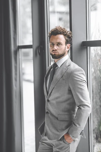 Confident businessman in suit with hands in pockets looking at camera — Stock Photo