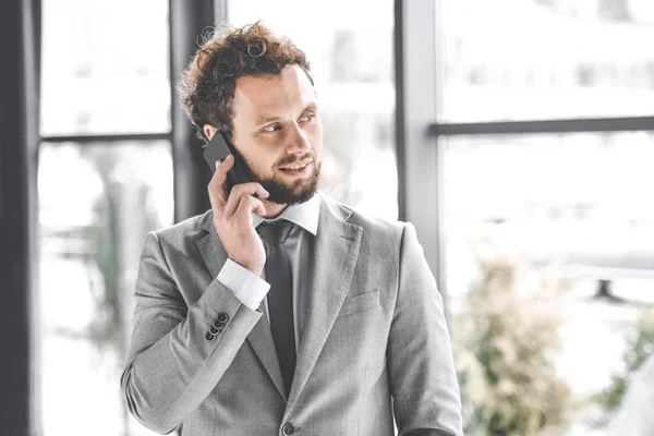 Портрет бизнесмена в костюме разговаривающего на смартфоне в офисе — стоковое фото