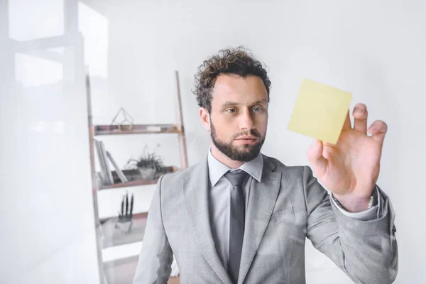 Portrait of focused businessman point at sticky note in office — Stock Photo