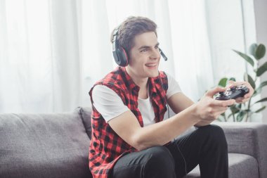 mutlu genç kızla evde joystick ile bilgisayar oyunu oynamak kulaklık