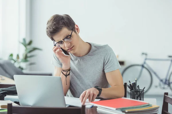 Student Mówi Smartfona Podczas Odrabiania Lekcji Laptopa Domu — Zdjęcie stockowe