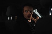 Seriöser männlicher Privatdetektiv mit Talkie-Walkie im Auto