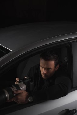 high angle view of paparazzi doing surveillance by camera from his car  clipart