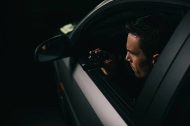 Erkek paparazzi gözetleme dürbünü tarafından arabadan yapıyor yan görünüm 