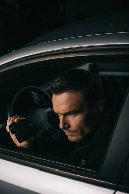 Erkek paparazzi gözetleme dürbünü tarafından arabadan yapıyor. 