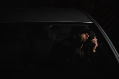 Arabaya walkie talkie kullanarak şapkalı erkek özel dedektif önden görünümü