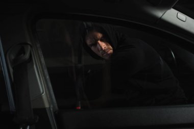 Araba penceresi dirsek tarafından sızmak isteyen ciddi erkek soyguncu