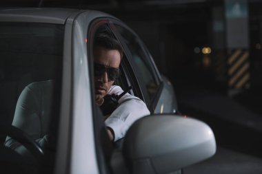 ciddi erkek gizli ajan gözetleme yapıyor ve arabaya walkie talkie kullanarak güneş gözlüğü