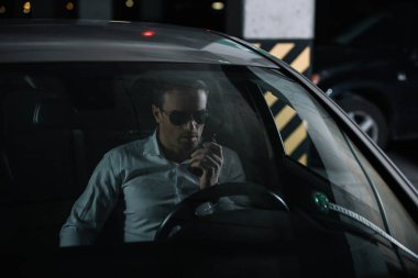 Erkek gizli ajan walkie talkie kullanarak ve arabada oturan güneş gözlüğü