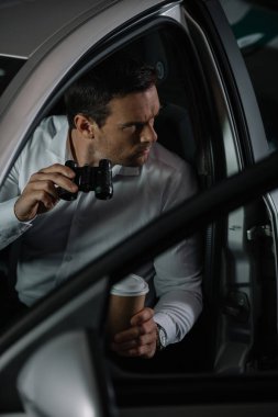 Gözetleme dürbünü tarafından arabadan yapıyor kahve fincanı ile gizli erkek aracının yüksek açılı görünüş