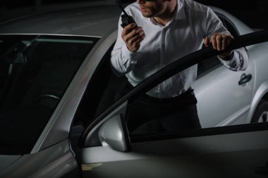 cropped image of male undercover agent using talkie walkie near car  clipart