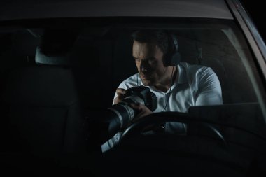 Araba lens ile fotoğraf makinesi tarafından casusluk Kulaklığımda erkek özel dedektif konsantre