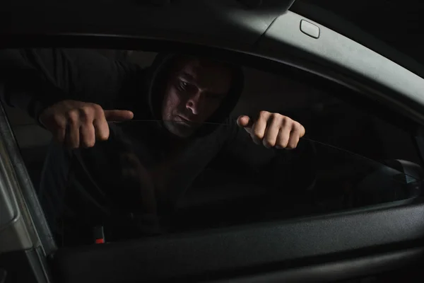 重点男子劫匪在黑色帽衫侵入汽车 — 图库照片