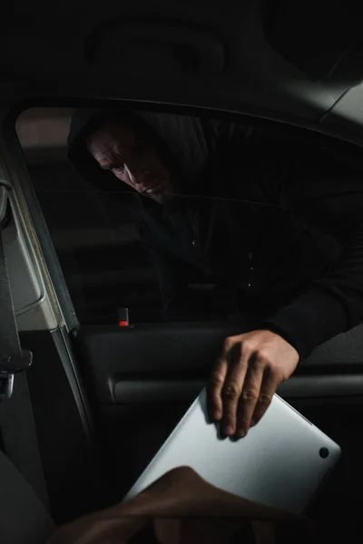 男性劫匪在黑色帽衫偷笔记本电脑的情况下 — 图库照片