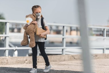 oyuncak ayı ve kitap ile köprüde, hava kirliliği kavram yürümeye koruyucu maske çocuk
