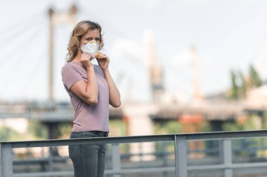 woman wearing protective mask on bridge and looking away, air pollution concept clipart