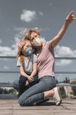 bir şeye köprü, hava kirliliği kavramı üzerinde koruyucu maske kızı işaret eden anne