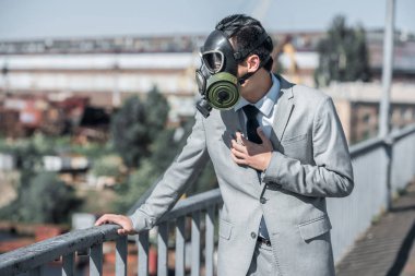 businessman in gas mask having problem with breathing on bridge, air pollution concept clipart