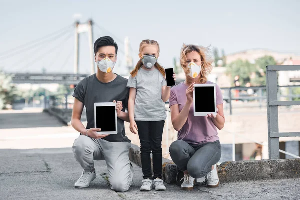 Multiculturele Familie Met Kind Beschermende Maskers Houden Van Gadgets Luchtvervuiling — Stockfoto