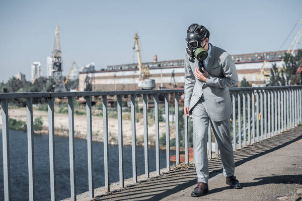 businessman in gas mask walking on bridge, air pollution concept