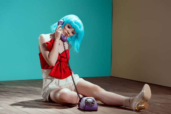 beautiful stylish female model sitting on floor and talking by rotary phone