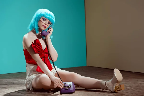 美丽的时尚女孩在蓝色假发坐在地板上说话的手机 — 图库照片