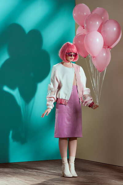 beautiful fashionable young female model holding pink balloons