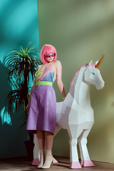 fashionable beautiful girl in pink wig leaning at unicorn