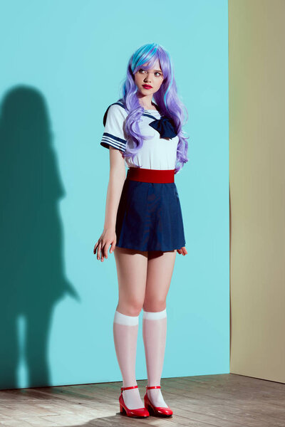 full length view of beautiful girl in bright wig and skirt standing and looking away in studio