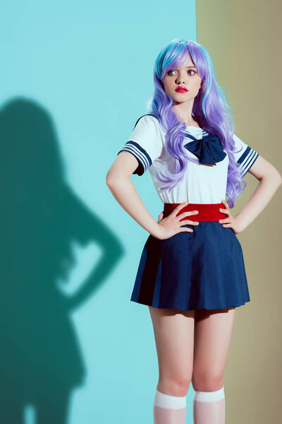 young beautiful woman in bright wig and skirt standing with hands on waist and looking away in studio