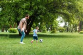 boční pohled na otce a syna hrát fotbal v parku