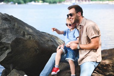 bir şeye işaret eden oğlu Park'ta Nehri yakınında baba