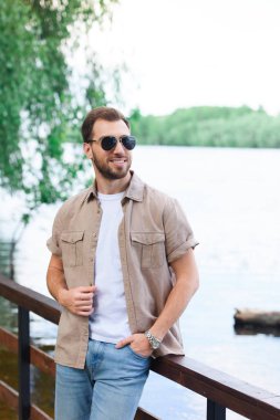 yakışıklı adam lake Park yakınındaki korkuluk üzerine eğilerek gülümseyen
