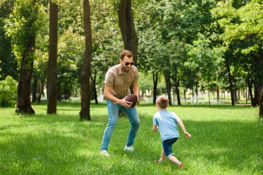 Baba ve oğul Amerikan futbolu birlikte parkta oynarken
