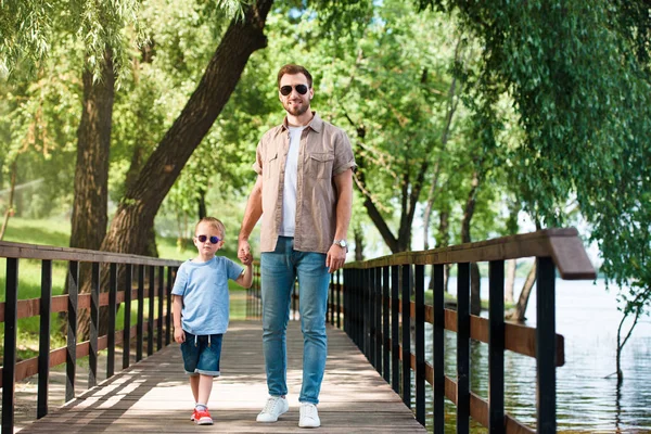 Ayah Dan Anak Berkacamata Hitam Bergandengan Tangan Dan Berjalan Jembatan — Stok Foto