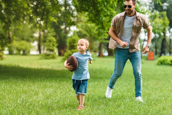 Отец Сын Бегают Американским Футбольным Мячом Парке — стоковое фото