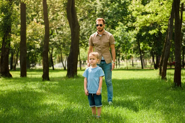 Ayah Dan Anak Berdiri Atas Rumput Taman Dan Memandang Jauh — Foto Stok Gratis