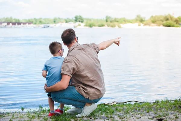 Back view of father pointing on something at river to son at park — Stock Image Back View Father Pointing Something River Son Park Stock Picture