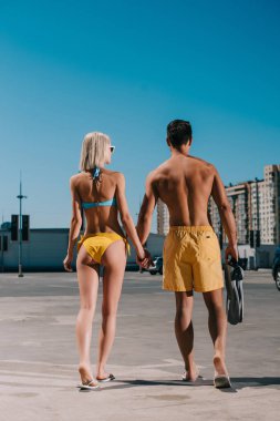 Dikiz palet Park üzerinde yürüme ile bikini ve yüzme şortu giymiş genç çekici çift