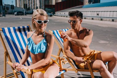 yakışıklı delikanlı kız geri Park üzerinde güneş koruyucu losyon uygulamak