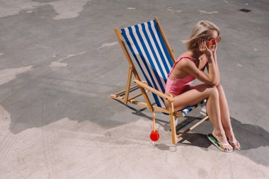 mutlu genç kadının güneşlenme asfalt üzerinde oturan yüksek açılı görünüş