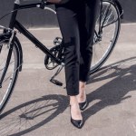 Tiro cortado de mulher de negócios em terno com café para ir de pé perto de bicicleta retro na rua