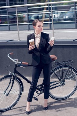 kahve ve smartphone ayakta sokakta retro Bisiklet yakınındaki genç iş kadını