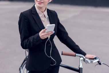 işkadını earphones ile smartphone ayakta sokakta retro Bisiklet yakınındaki içinde kırpılmış atış